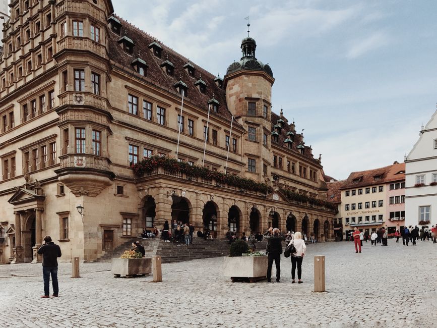 People walking near the historic town hall in Rothenburg, Germany's medieval town square.