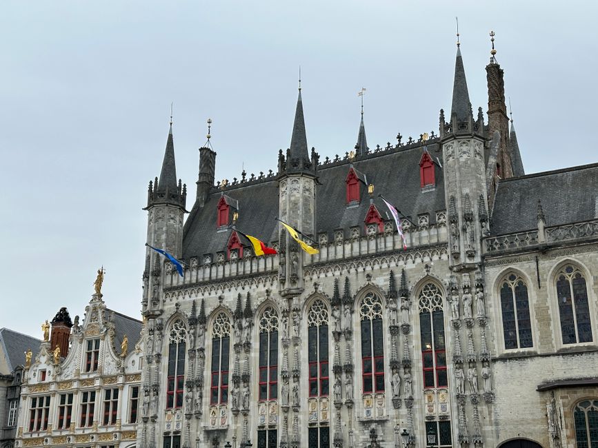 Historic Gothic architectural marvel of Bruges city hall with flags displayed.