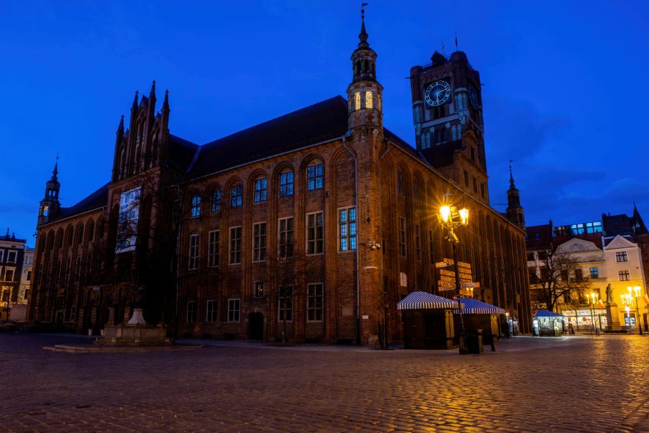 Beautiful illuminated historic town hall in Poland captured at dusk, featuring Gothic architecture.